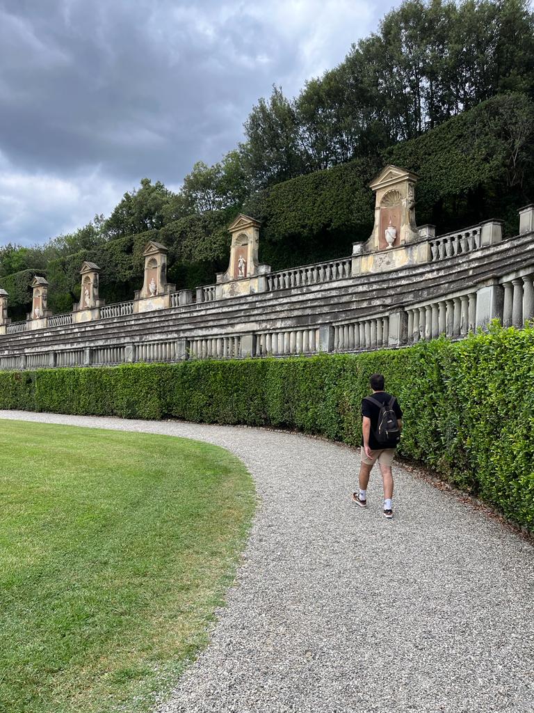 Okan walking along a garden path beside a stone terrace